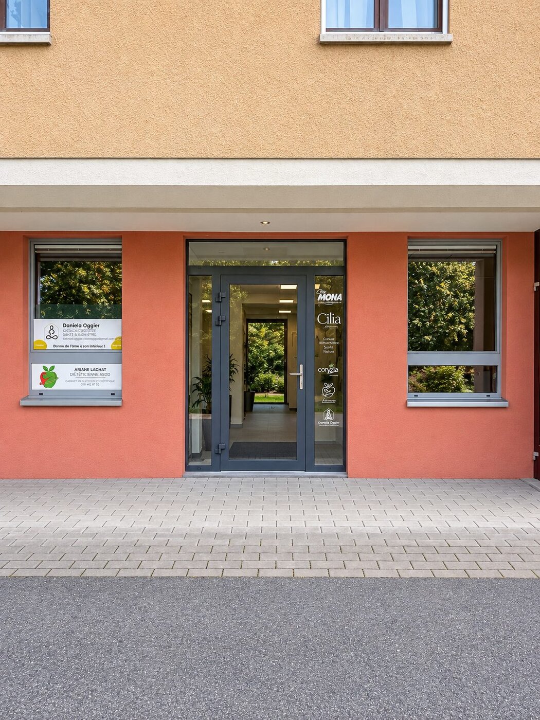 L'entrée du bâtiment, avec l'enseigne Chez Mona sur la porte vitrée